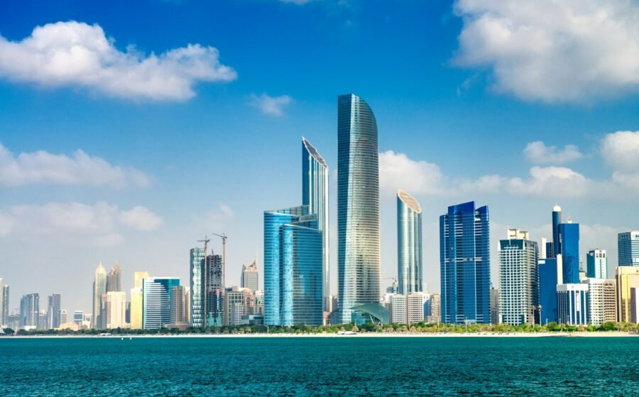 Abu Dhabi waterfront skyline across blue water in daylight.