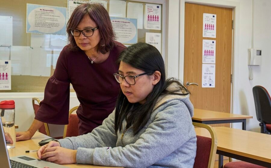 Illustrative photograph of two adults collaborating on a computer, representing curriculum volunteering; not MAAT K12 volunteers