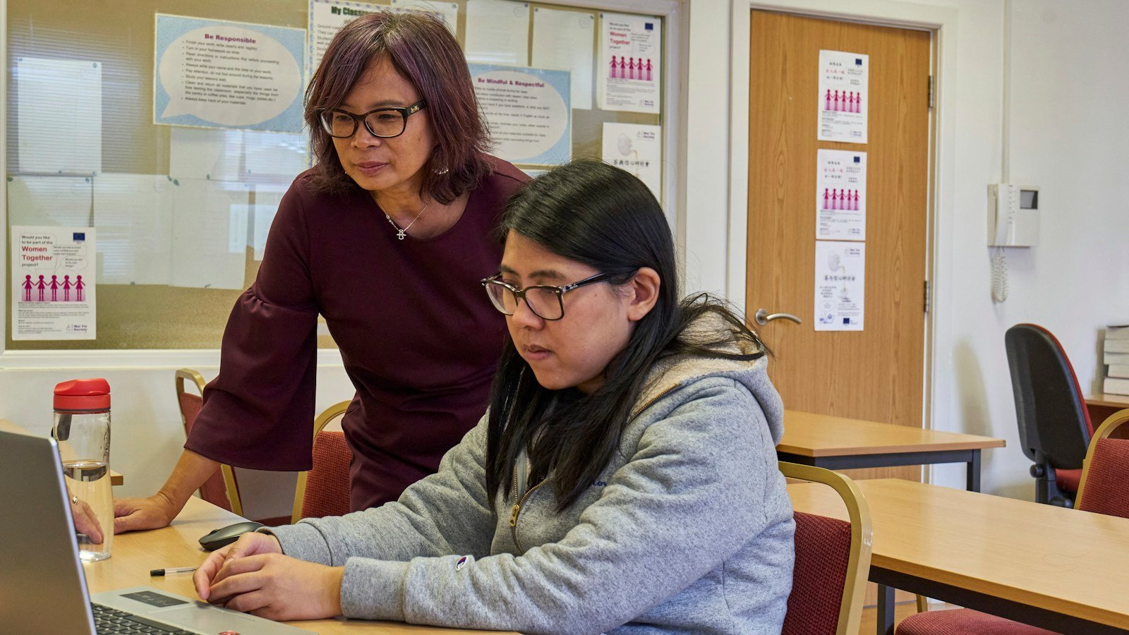 Illustrative photograph of two adults collaborating on a computer, representing curriculum volunteering; not MAAT K12 volunteers