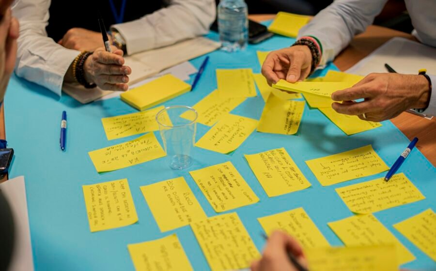 People collaborating around a planning workshop table, illustrating community-led grant proposals