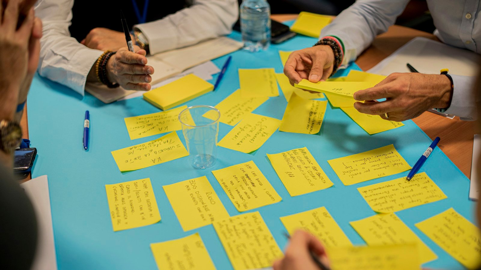 People collaborating around a planning workshop table, illustrating community-led grant proposals