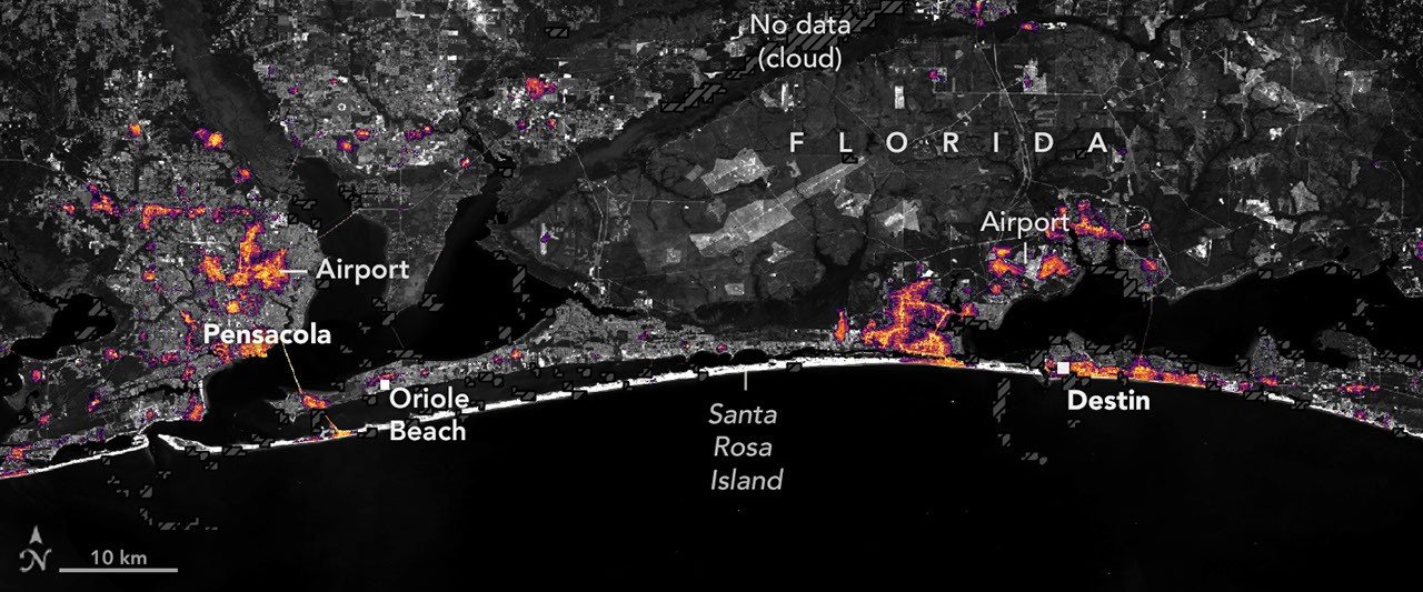Black Marble HD map of nighttime lights near Pensacola and Destin on October 11, 2026, with dimmer areas and a marked cloud-related data gap.