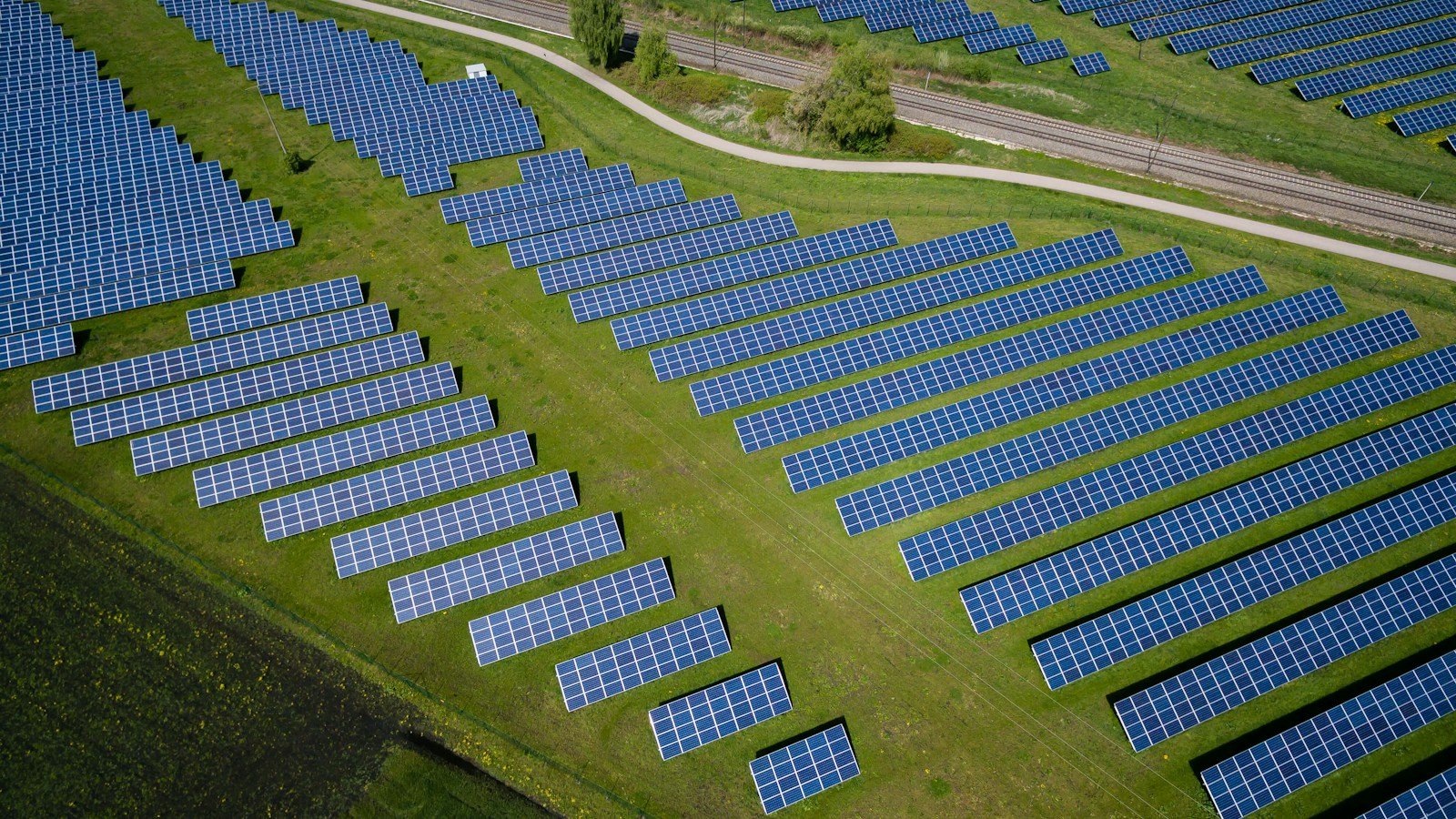 Aerial view of solar panels in a grassy landscape, representing renewable energy in future sustainable communities; illustrative, not a Khemetic Nation development.
